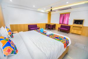 a bedroom with a large bed and two purple chairs at FabExpress Picnic Plaza Mylapore in Chennai
