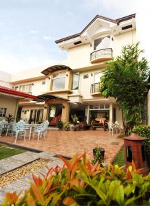 ein Haus mit einer Terrasse mit Stühlen und Tischen in der Unterkunft Harbour Gardens Tourist Inn in Tagbilaran