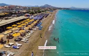 a beach with umbrellas and people in the water at Assos Villa in Káto Ássos