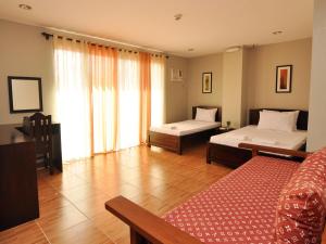 a bedroom with two beds and a large window at Harbour Gardens Tourist Inn in Tagbilaran City