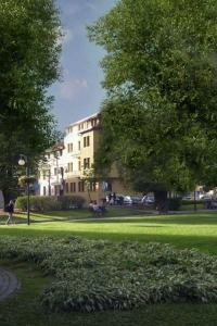 a park with a building and a tree and grass at Hotel Slovan in Žilina