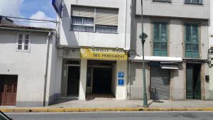 un edificio con un letrero amarillo en la parte delantera en Del Peregrino, en Arzúa