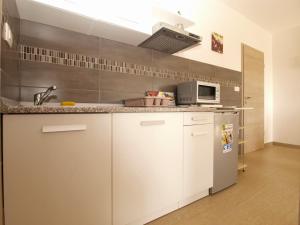 a kitchen with white cabinets and a microwave at Apartments Biljana 1480 in Ližnjan