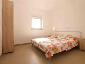 a bedroom with a bed with a floral bedspread and a window at Apartments Biljana 1480 in Ližnjan