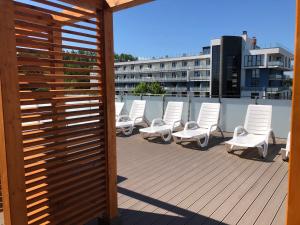 grupa białych krzeseł siedzących na tarasie w obiekcie Apartament Superior Pastelowy Przy Plaży w Kołobrzegu