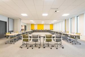 une grande salle de conférence avec une grande table et des chaises dans l'établissement Novotel Charleroi Centre, à Charleroi