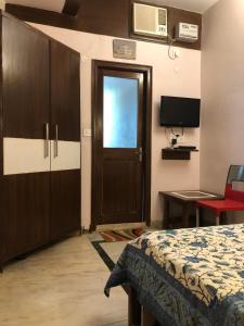 a room with a bed and a door and a television at Sailors Home - C6, Vasant Kunj in New Delhi