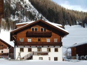a large wooden building with a balcony in the snow at Haus Gartenheim in Kals am Großglockner