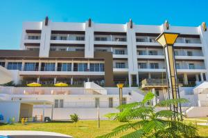 ein großes weißes Gebäude mit gelben Sonnenschirmen davor in der Unterkunft Baobab Tree Hôtel & Spa in Mahajanga