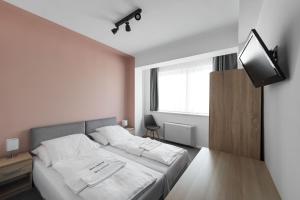 a white bedroom with a bed and a television at Hotel Chesscom in Budapest