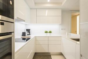 リスボンにあるFLH Rato Spacious Apartmentの白いキッチン(白いキャビネット、電化製品付)