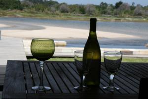Una botella de vino y dos copas en una mesa en Twin Rivers Villa, en Plettenberg Bay