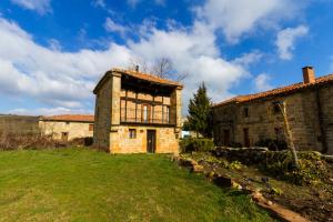 una vieja casa de piedra en un campo al lado de un edificio en Casas Canduela, en Canduela