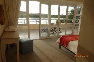 Un dormitorio con una cama y vista a un balcón. en Twin Rivers Villa, en Plettenberg Bay