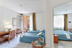 a hotel room with two beds and a desk at Hotel Yacht Club in Marciana Marina