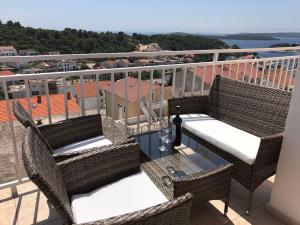 a balcony with wicker chairs and a table with a bottle of wine at Apartments and Rooms Jasna in Hvar