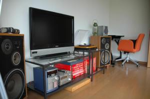 een woonkamer met een flatscreen-tv en luidsprekers bij 熱海貸切り別荘網代の家 in Ajiro