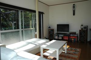 ein Wohnzimmer mit einem weißen Sofa und einem Tisch in der Unterkunft 熱海貸切り別荘網代の家 in Ajiro