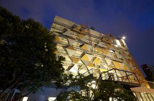 a building with a yellow and white facade at night at Anya Nana at Sukhumvit Bangkok in Bangkok