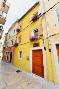 a yellow building with a red door on a street at Harvey's luxury rooms in Zadar