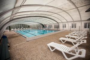 una piscina con sedie a sdraio bianche in un edificio di Village Vacances Passion L'Emeraude a Damvix