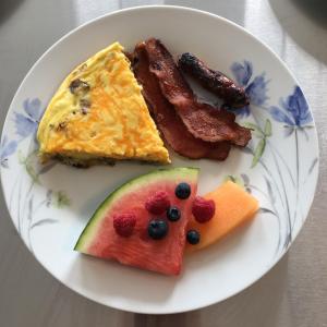 un plato de desayuno con huevos tocino y fruta en Come from Away B&B en Digby