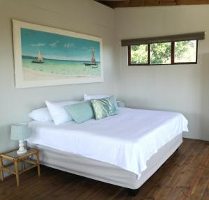 a bedroom with a bed with white sheets and a window at Dune View Cottage in Sodwana Bay