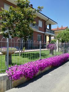a fence with purple flowers in front of a building at B&B Mary in Alba