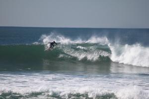 a man riding a wave on a surfboard in the ocean at Natural Mystic Hostel in Costa da Caparica