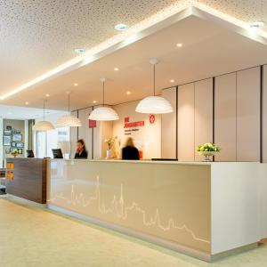 an office lobby with a reception counter and pendant lights at Johanniter Gästehaus in Münster