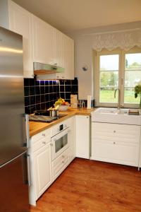 una cocina con armarios blancos y fregadero en Cottage, en Buchholz