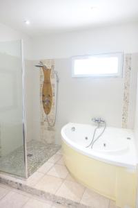 baño con bañera blanca y guitarra en Mas du Roc, en Saint-Nazaire