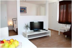 a living room with a television and a table with fruit at Apartments Ercegovic in Primošten