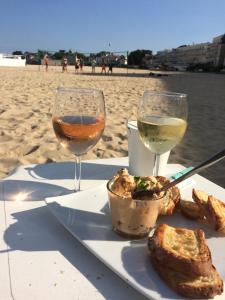 a plate of food and two glasses of wine on the beach at La Plage - Appartement face mer sur la plage in Le Pouliguen +23 photos