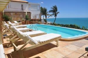 piscina con sedie a sdraio e oceano di Pousada Azul Marinho a Canoa Quebrada