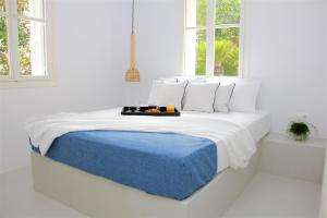 a white bedroom with a bed with a blue blanket at 30villa Rd in Rhodes Town