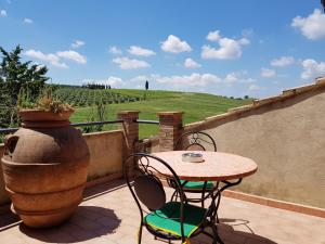 d'une terrasse avec une table, des chaises et un vase. dans l'établissement Agriturismo Bio Le 4 Stagioni, à Porrona