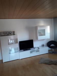 a white living room with a tv and a chair at Ferienwohnung Gogelhopf in Unterschneidheim