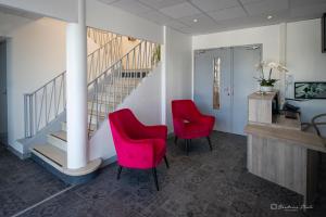a lobby with two red chairs and a staircase at Hôtel George Sand in La Seyne-sur-Mer