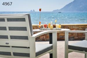 a table with drinks on it next to the ocean at Hôtel George Sand in La Seyne-sur-Mer
