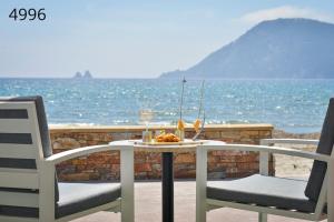 a table with a glass of wine and two chairs at Hôtel George Sand in La Seyne-sur-Mer