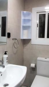 La salle de bains est pourvue d'un lavabo blanc et de toilettes. dans l'établissement Apartamentos Atlas Terrassa III, à Terrassa