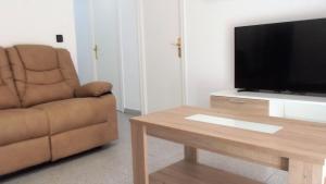 a living room with a couch and a television and a table at Apartamentos Atlas Terrassa III in Terrassa