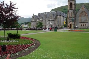 a large building with a green lawn and a church at Alexandra Hotel in Fort William