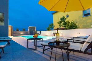 ein Pool mit Tischen und Stühlen und ein gelber Regenschirm in der Unterkunft Lucky Luke Pool Apartments in Novalja