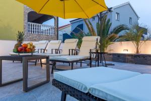 a patio with chairs and tables and a yellow umbrella at Privilege Pool Apartments in Novalja