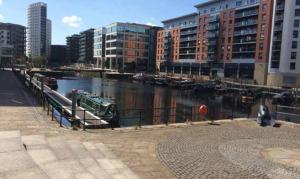 a river with boats docked next to some buildings at Prime Apartments Leeds in Leeds