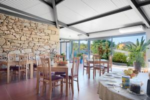 uma sala de jantar com mesas e cadeiras e uma parede de pedra em Casas de Sequeiros em Sequeiros