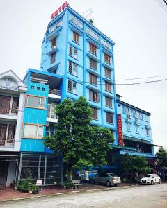 Tuyên Quang的住宿－Thành Trung Hotel，一座蓝色的建筑,前面有汽车停放