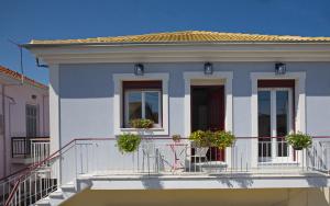 ein weißes Haus mit Topfpflanzen auf einem Balkon in der Unterkunft Casa di fiori in Lefkada Town